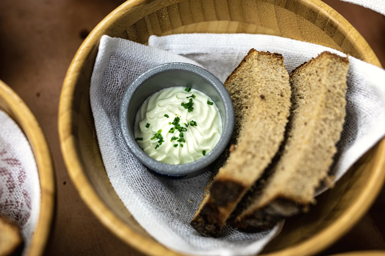 Scheiben selbstgebackenes Bärlauchbrot im Korb mit Kräutercreme