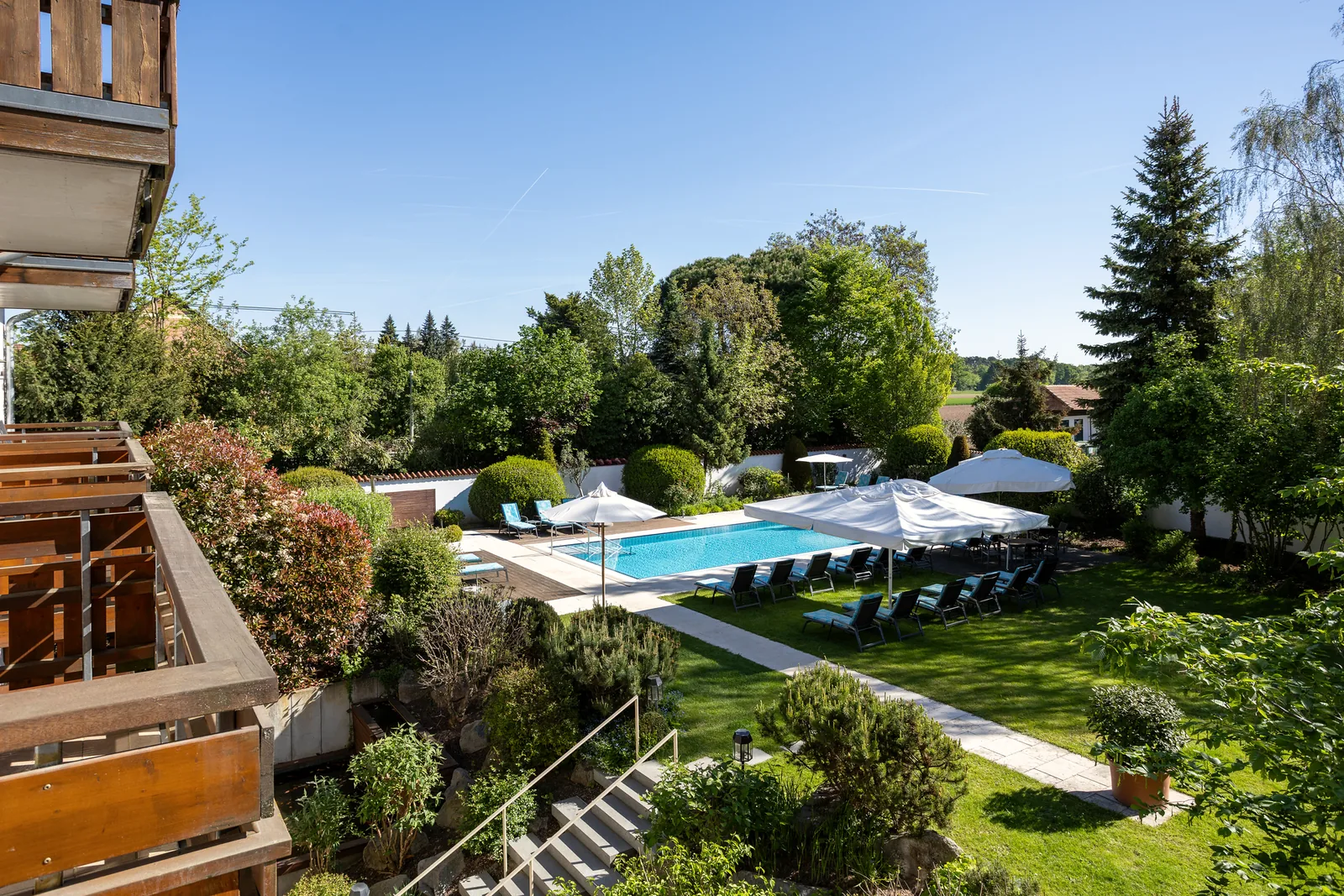 Blick vom Balkon eines Zimmers auf den Garten mit Außenpool und alten Bäumen des Hotel Krone