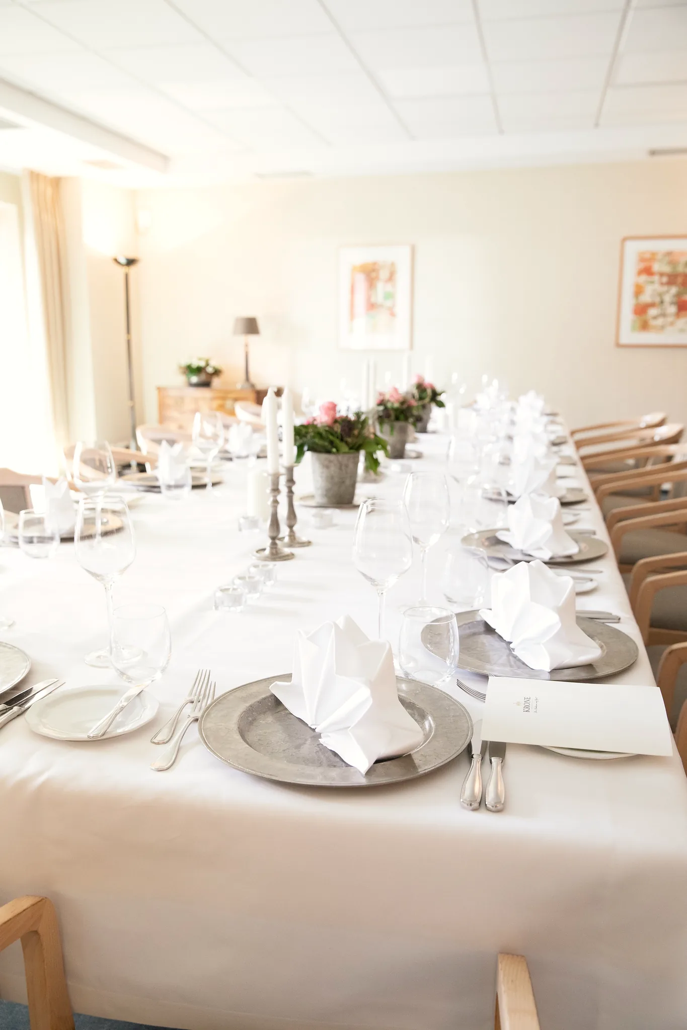 Lange gedeckte Tafel mit rosa Blumen und Kerzen im Hotel Krone