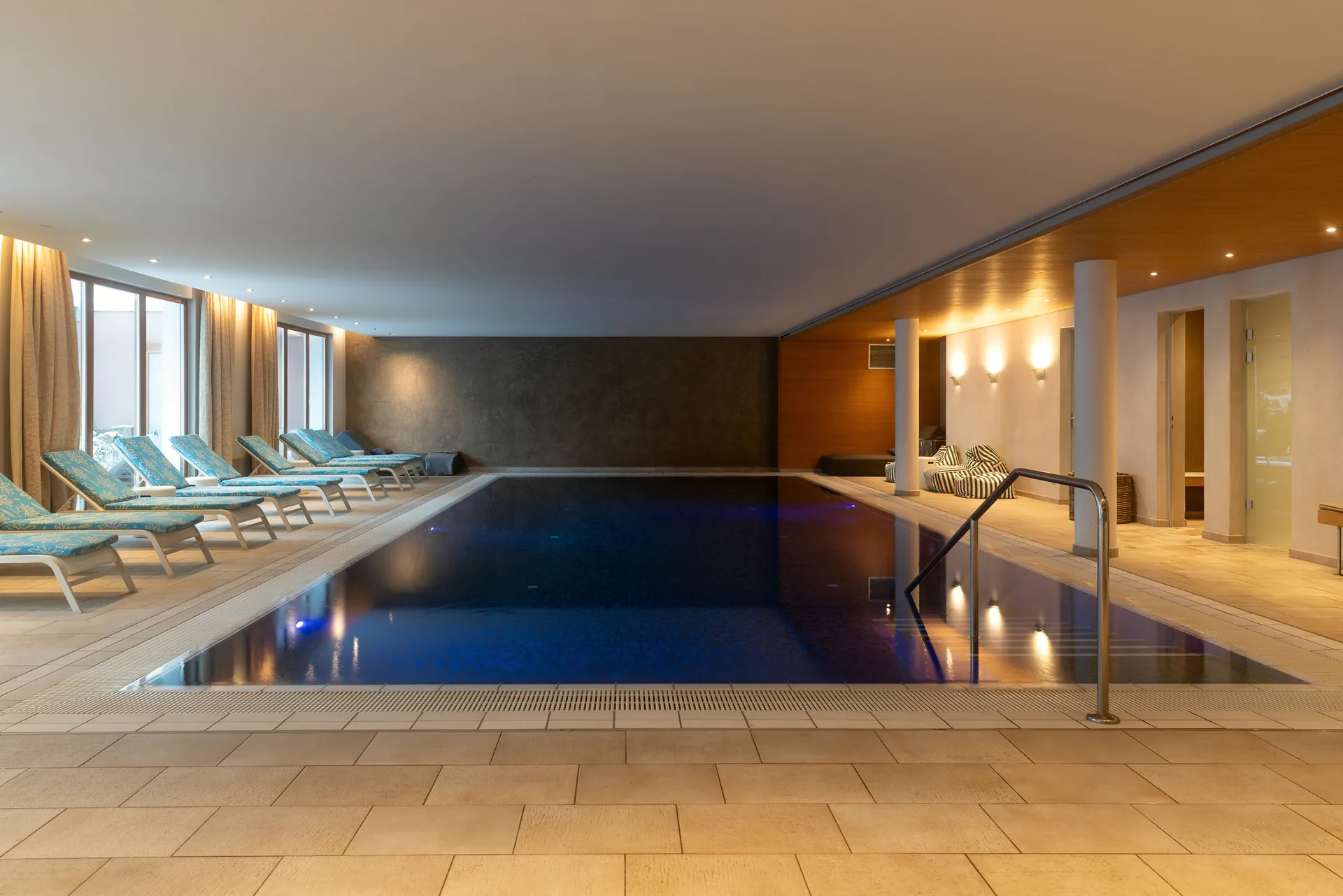 Innenpool des Hotel Krone am Abend, Holzdecke, Liegen am Beckenrand, warmes Licht spiegelt sich im Wasser