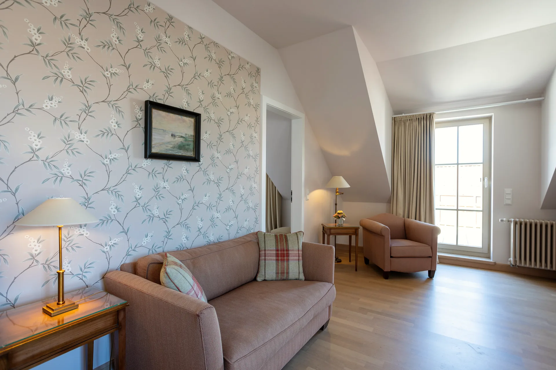 Helle Junior Suite mit Sofa, Sessel und Blick zum Schlafbereich im Hotel Krone