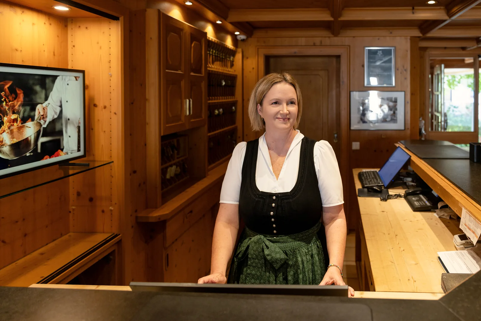 Mitarbeiterin in Tracht steht an der holzvertäfelten Rezeption des Hotel Krone