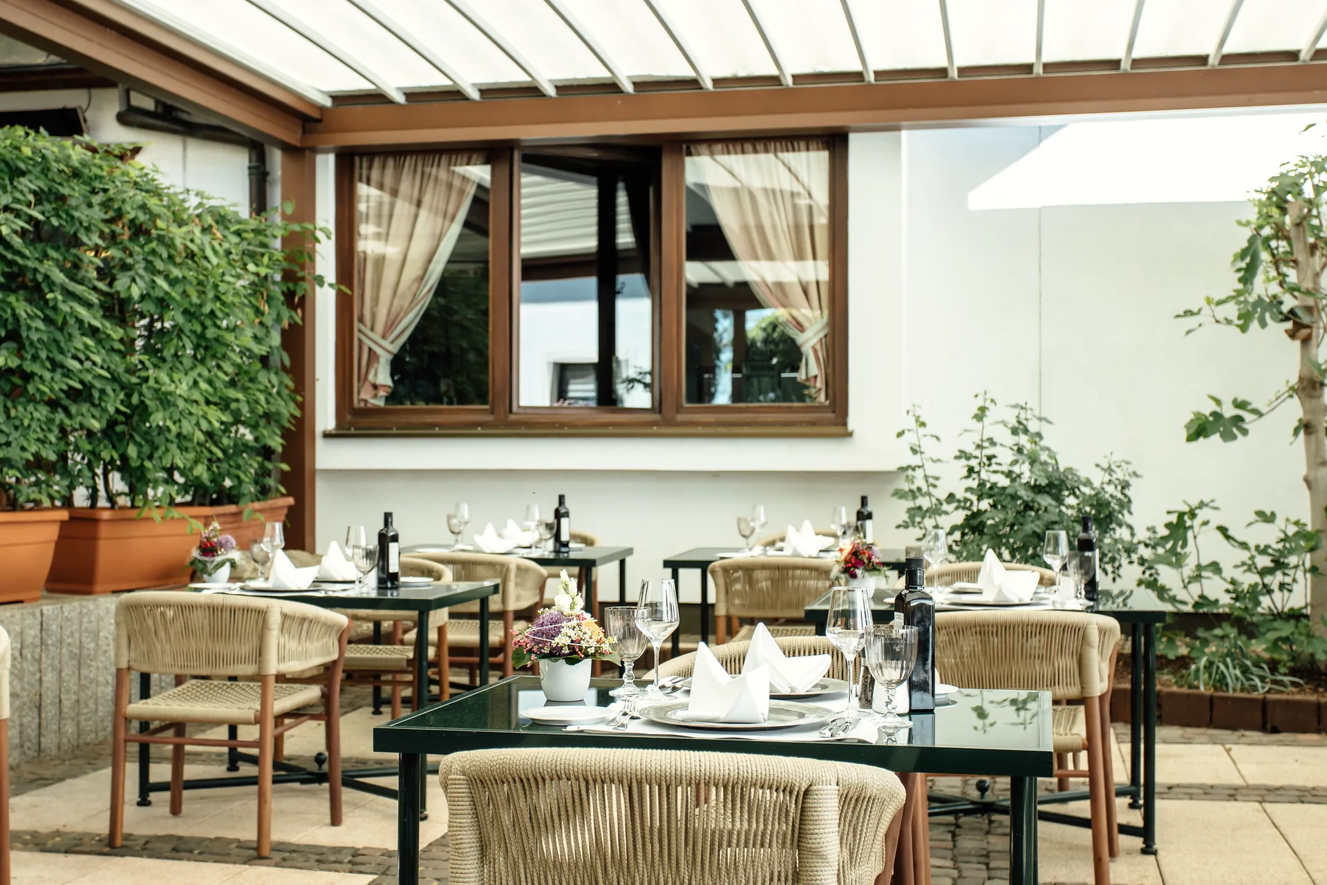 Gedeckte Tische unter der Pergola auf der Terrasse des Hotel Krone, umgeben von Pflanzen