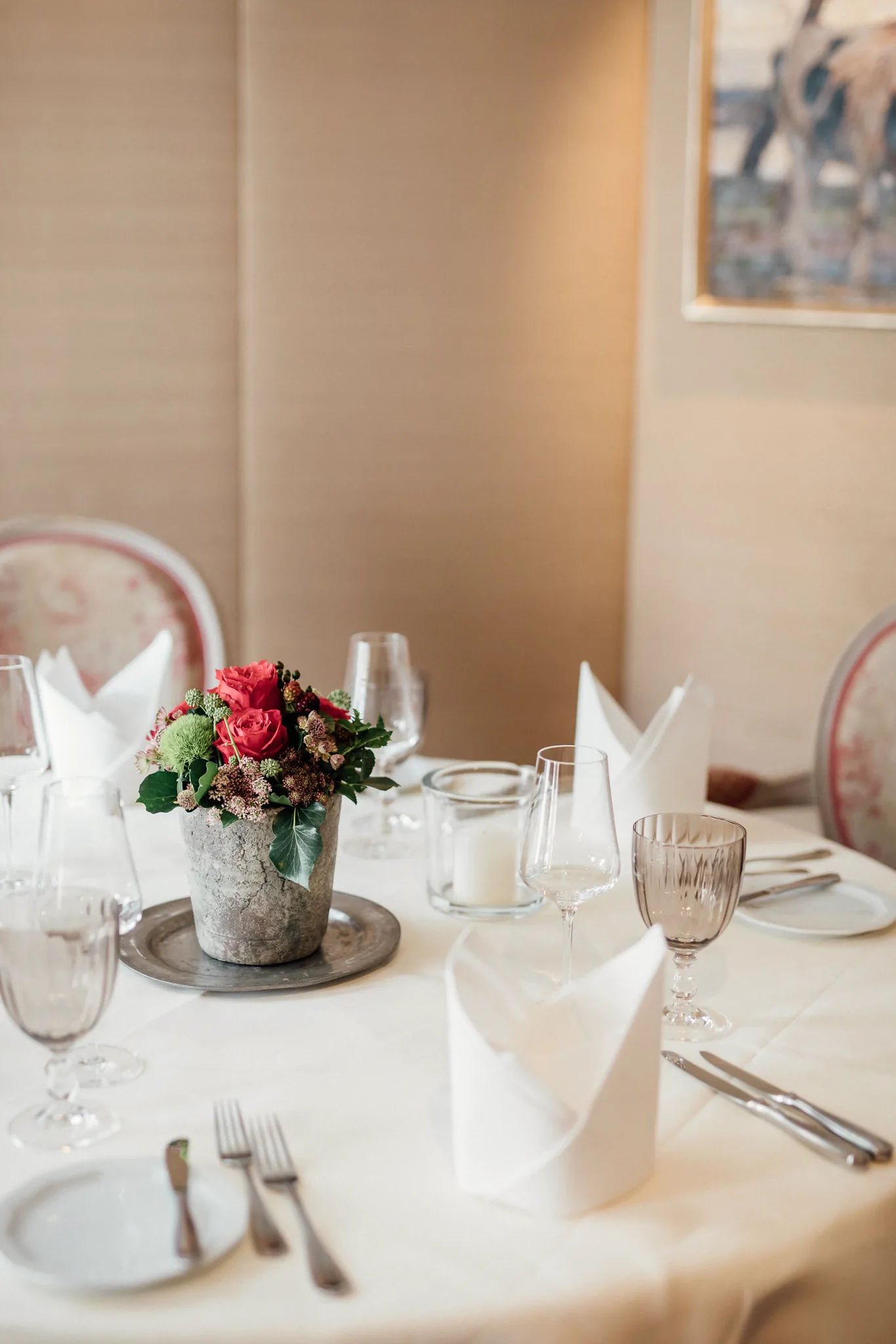 Kleiner gedeckter Tisch mit rosa Blumen und gepolsterten Stühlen im Restaurant des Hotel Krone