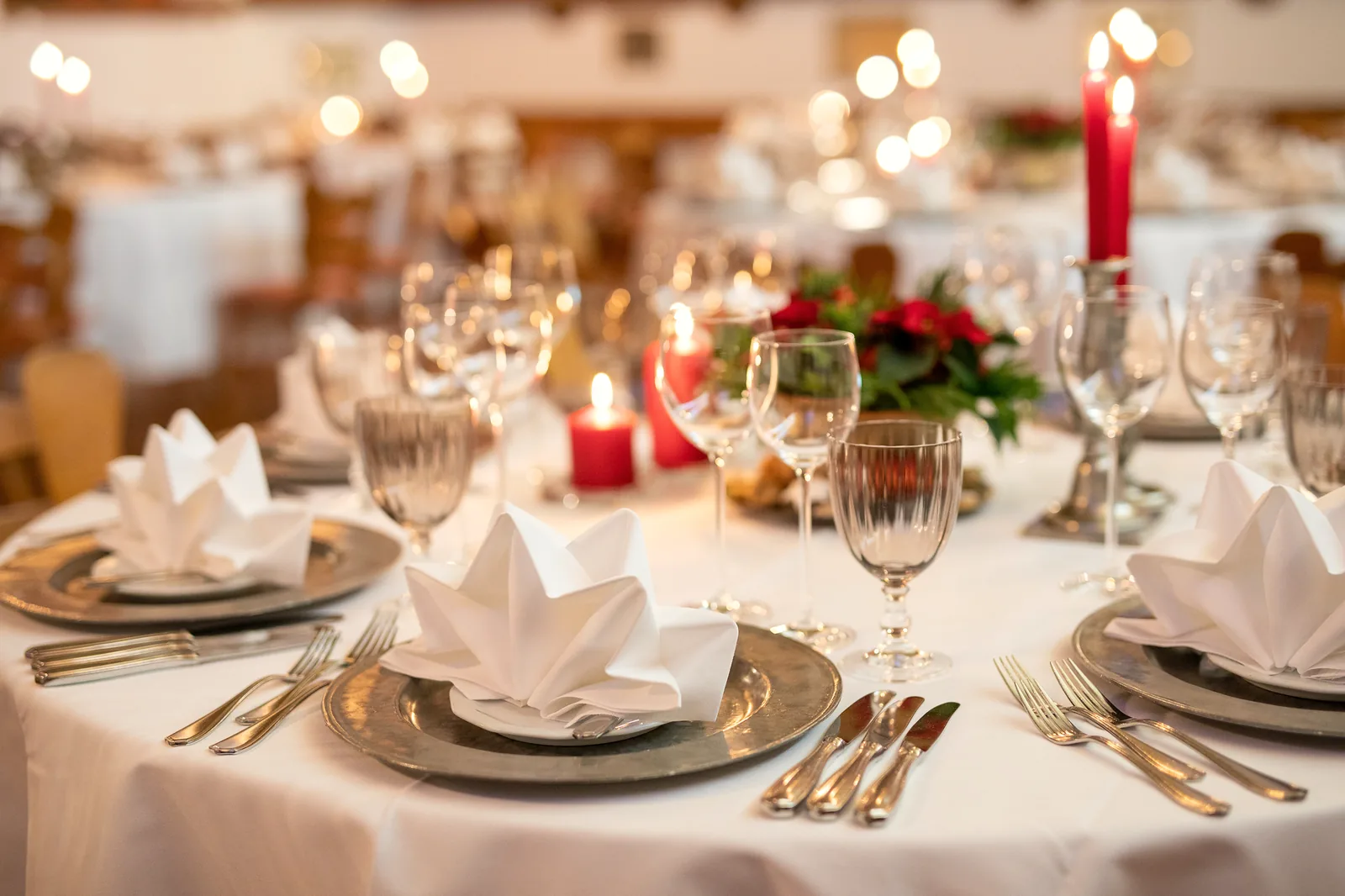 Gesteck aus roten Rosen, Tannengrün und Kerzen auf einer Festtafel im Hotel Krone