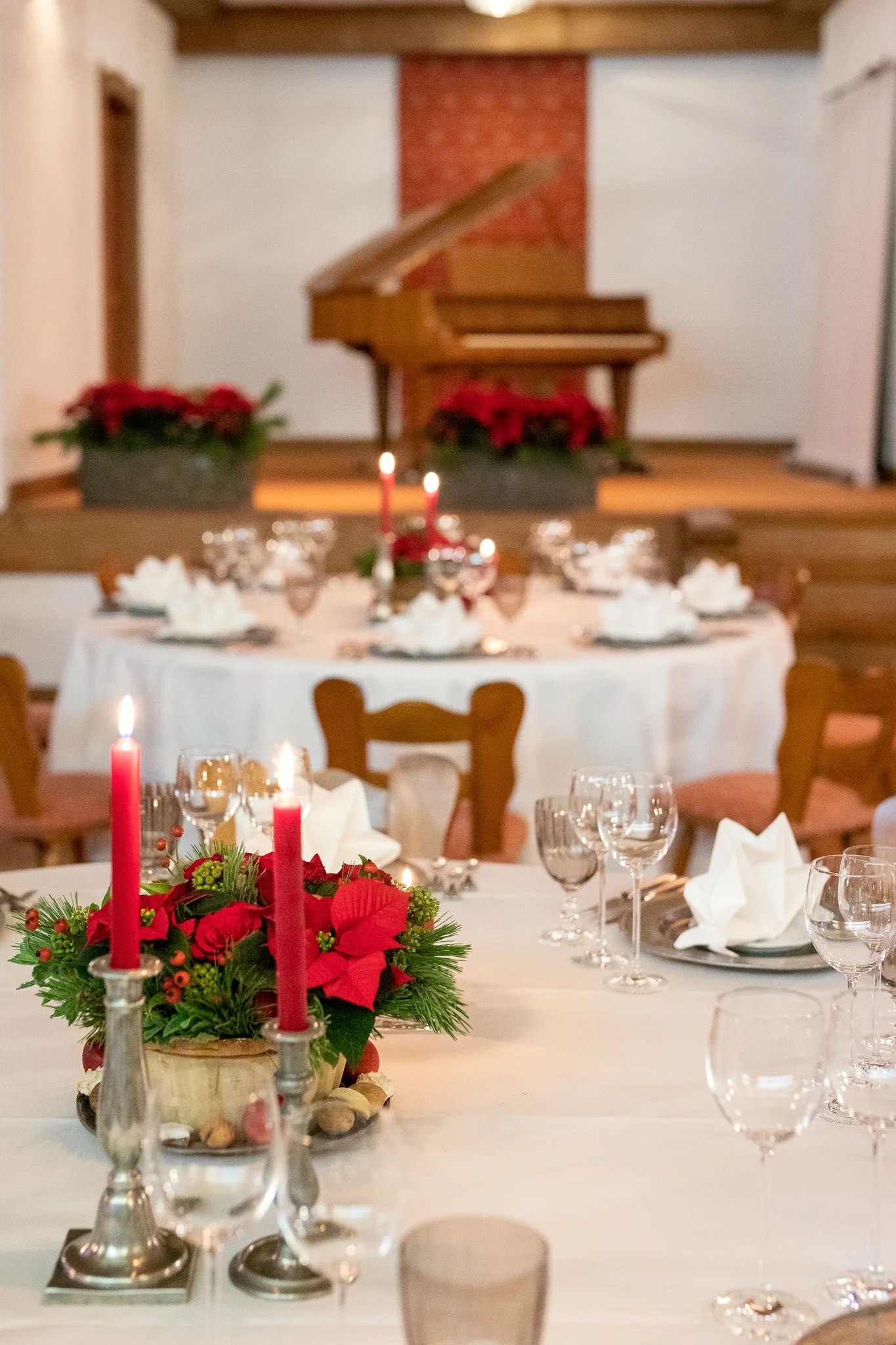 Weihnachtlich gedeckter Tisch mit roten Rosen und Kerzen, im Hintergrund das Klavier im Hotel Krone