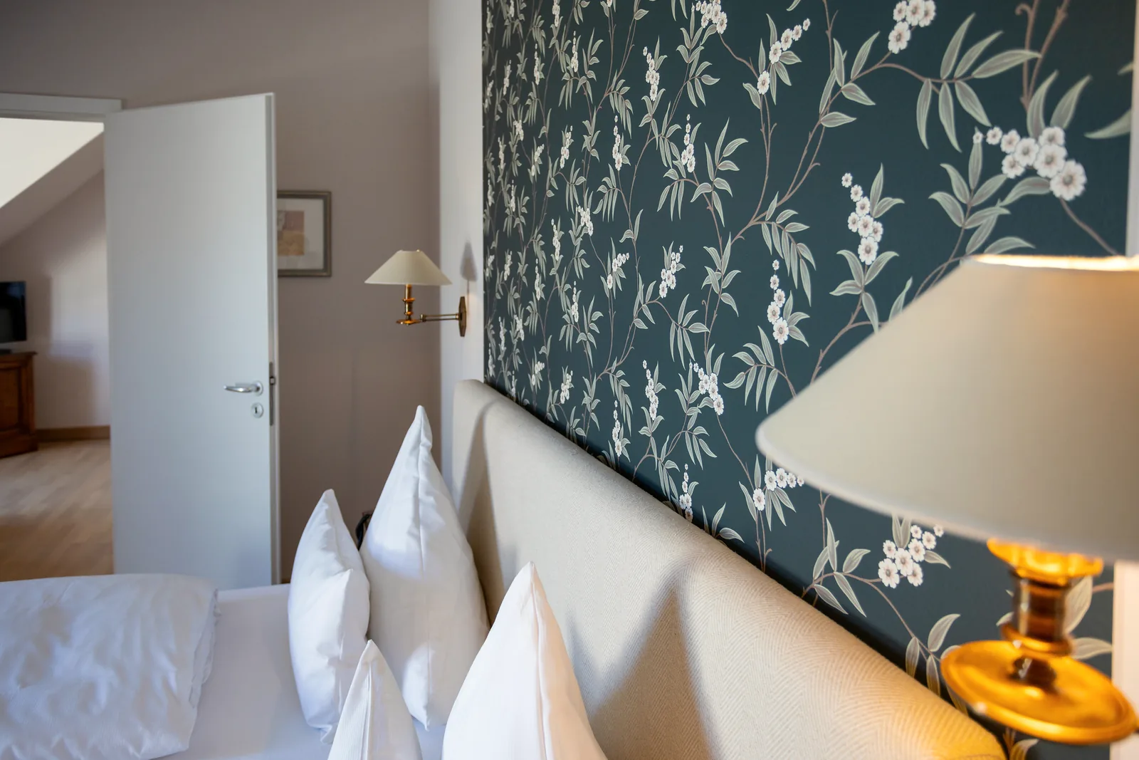 Nachttischlampe und Kissen im Tageslicht am Fenster eines Zimmers im Hotel Krone
