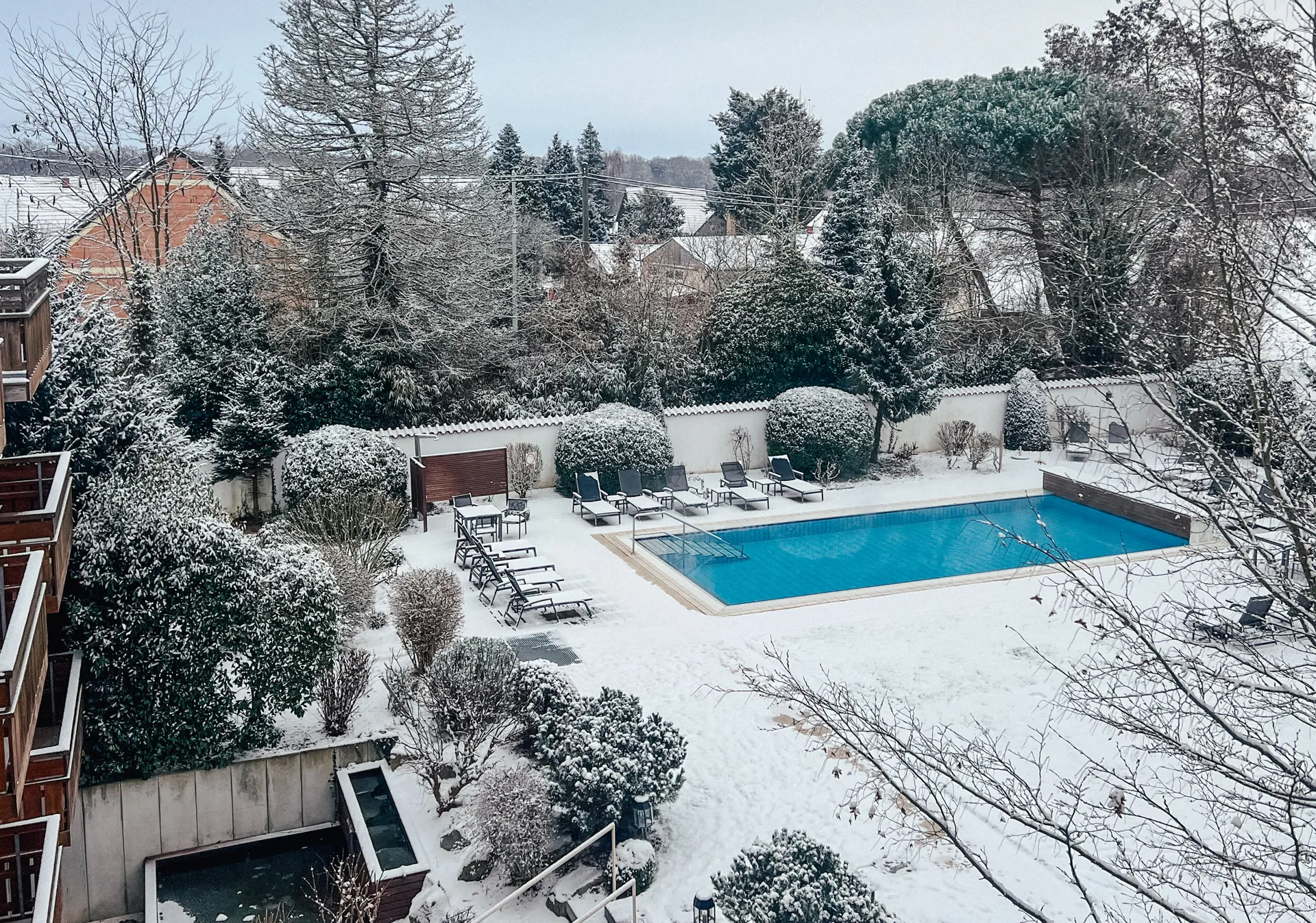 Blick von oben auf den beheizten Außenpool im verschneiten Garten des Hotel Krone