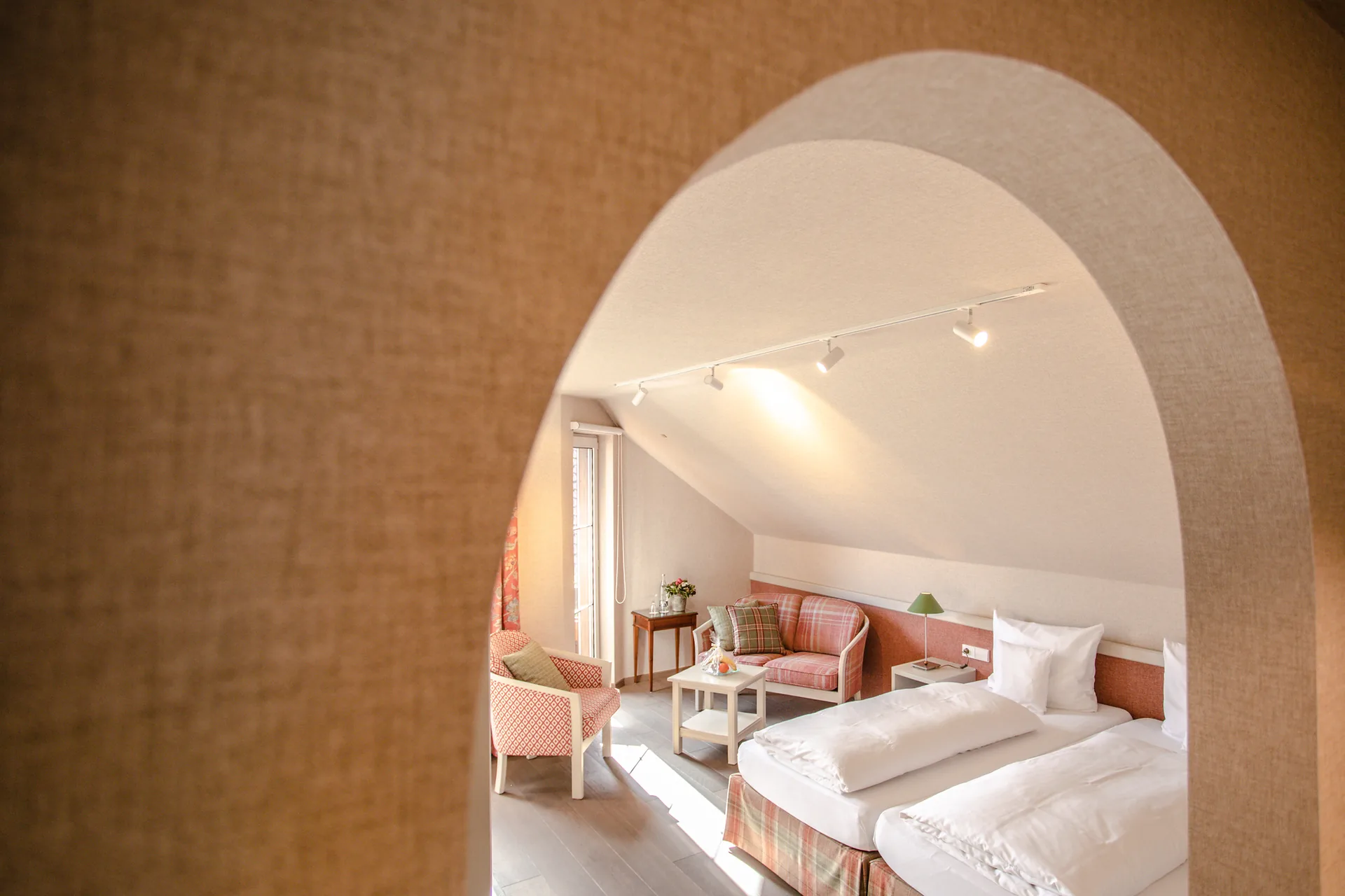 Blick durch den Bogendurchgang auf Bett und Sitzecke im Doppelzimmer Classic