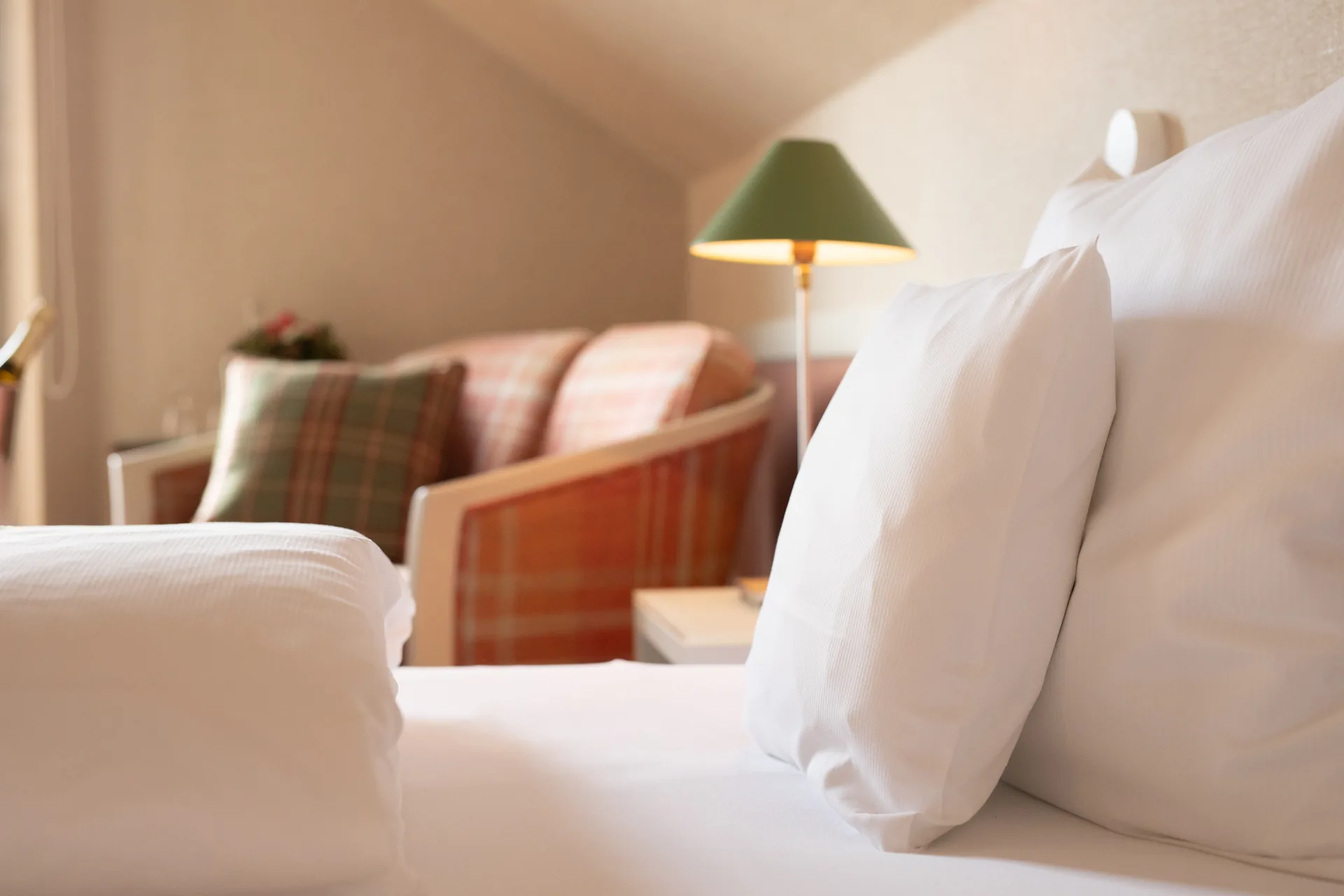Kissen auf dem Doppelbett, dahinter Sessel und grüne Leselampe im Doppelzimmer Classic