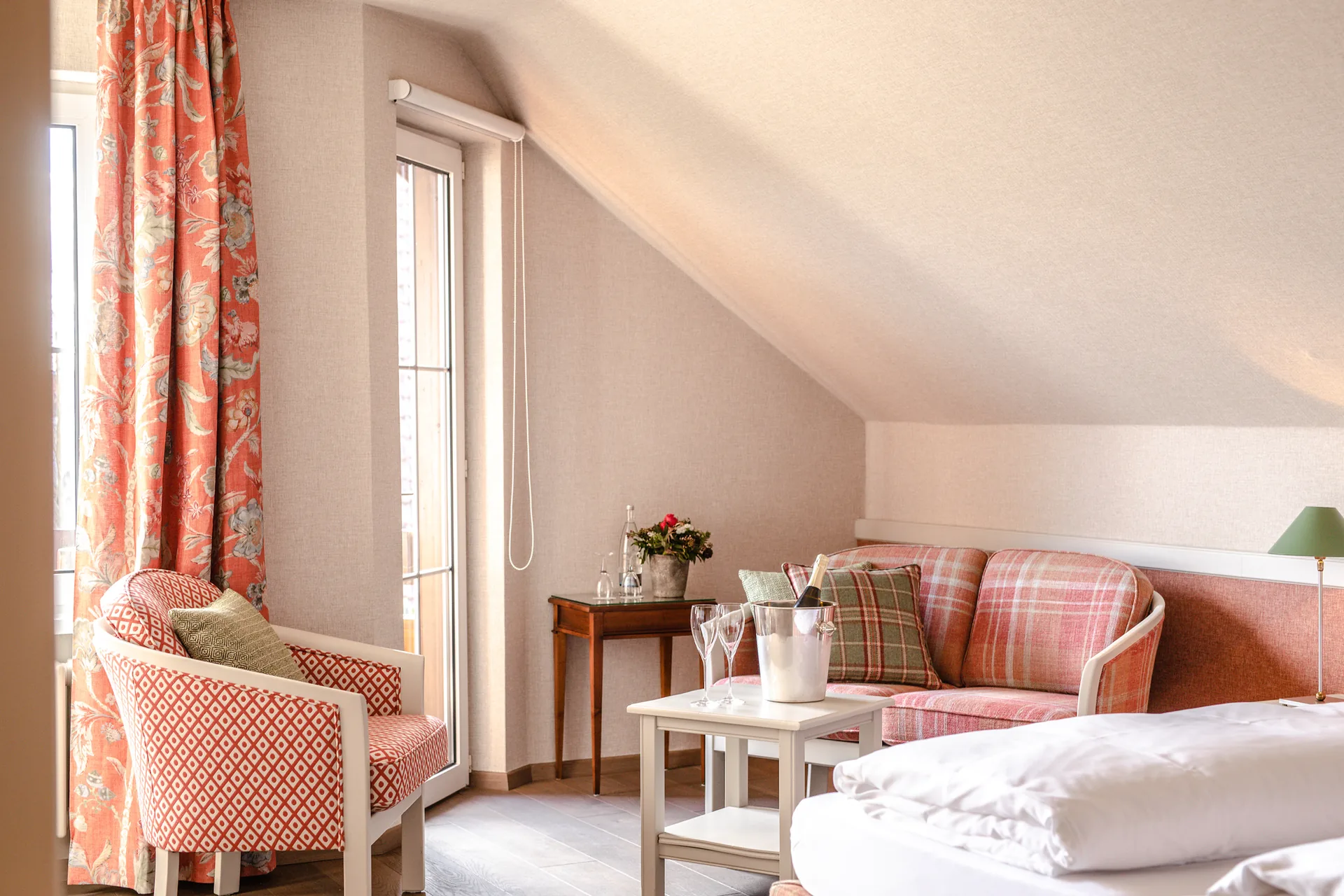 Sitzecke mit kariertem Sofa und Sessel an der Balkontür im Doppelzimmer Classic