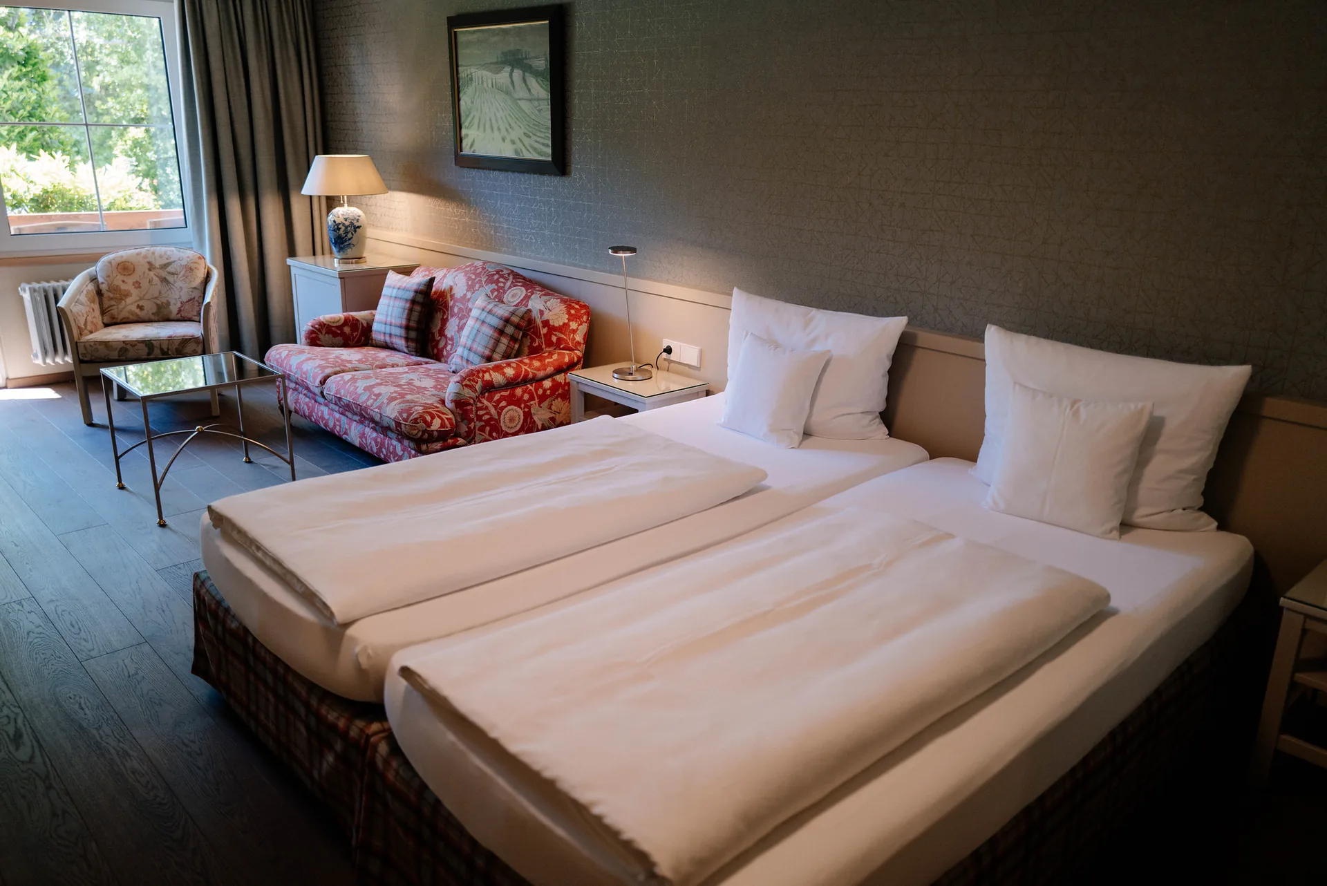 Doppelzimmer Classic mit Doppelbett, Sitzecke mit Blumensofa und Fenster zum Garten