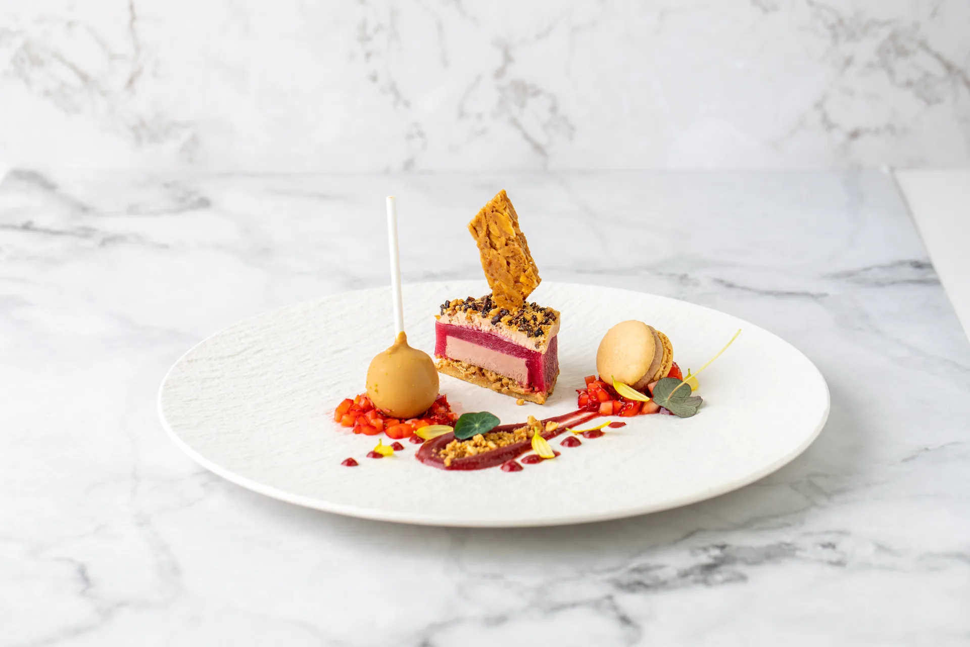 Dessert mit Himbeere, Sorbet und Krokant auf weißem Teller