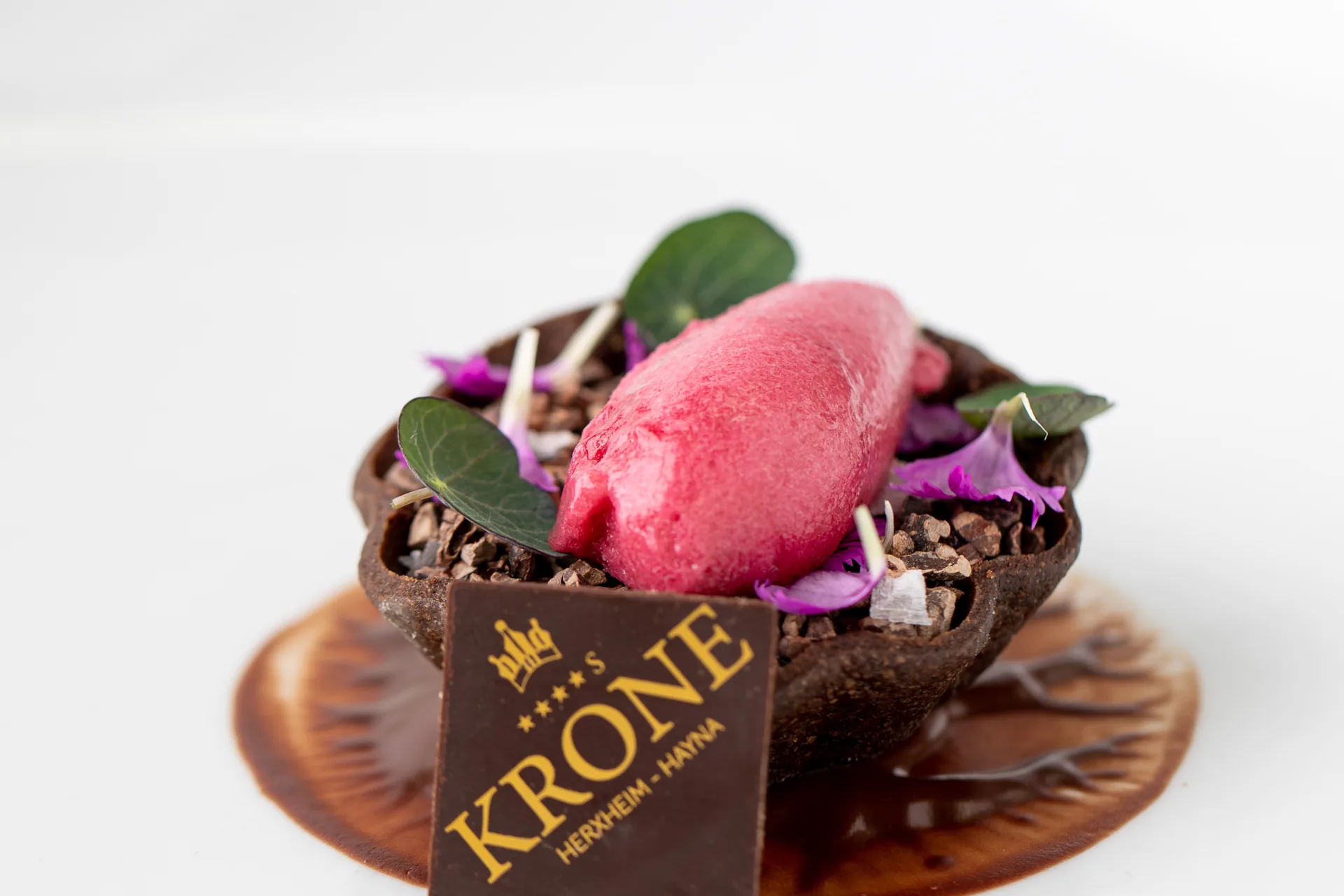 Schokoladendessert mit Krone-Schriftzug und Himbeere