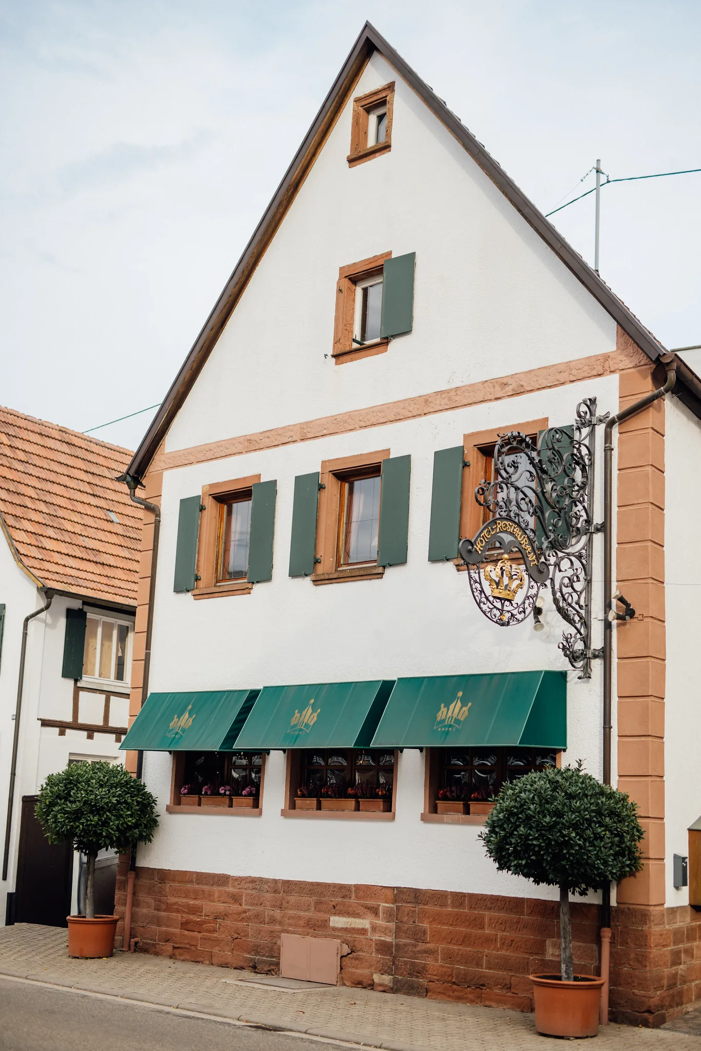 Fassade des Hotel Krone mit grünen Fensterläden, Markise und Wirtshausschild