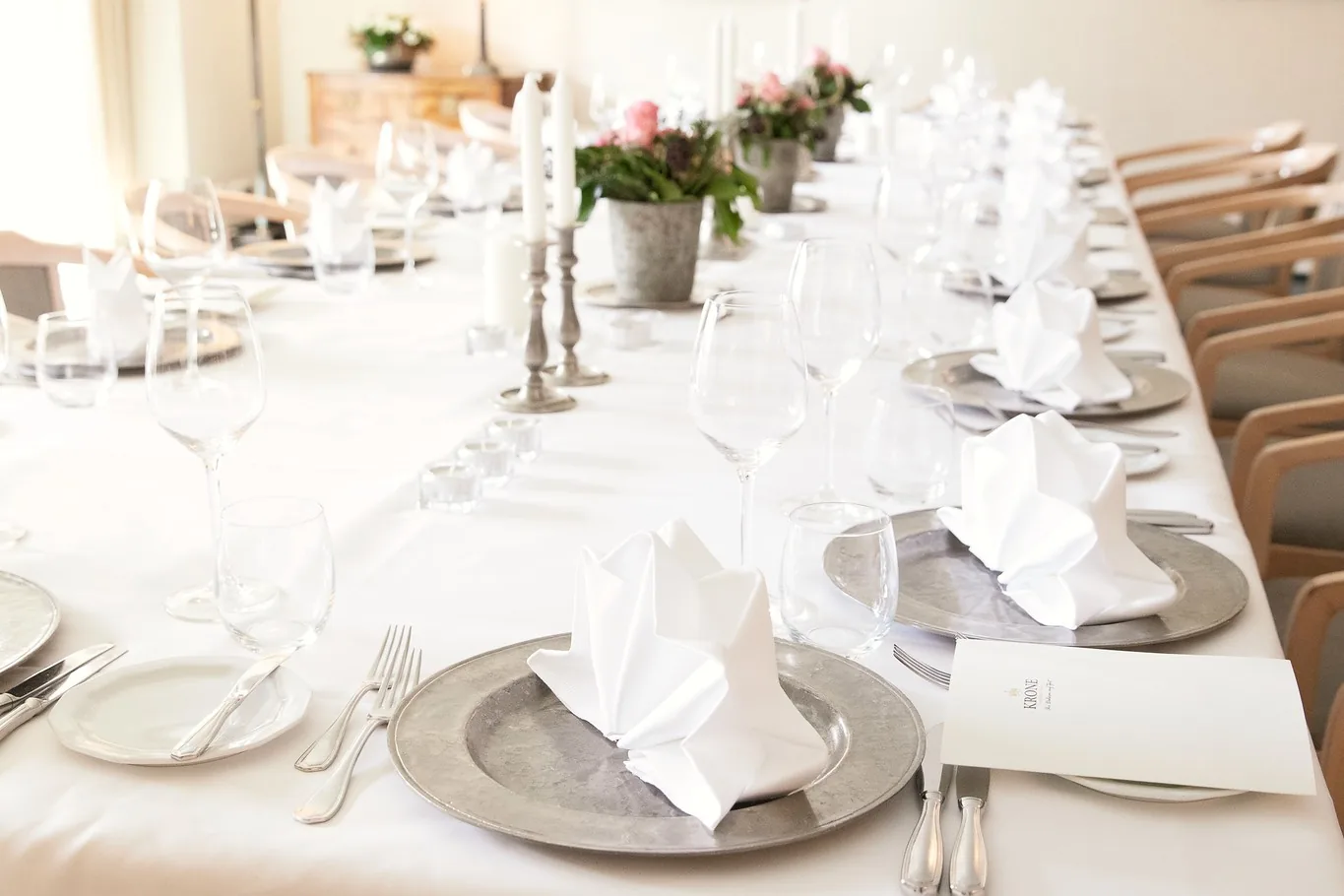 Lange gedeckte Tafel mit rosa Blumen und Kerzen im Hotel Krone