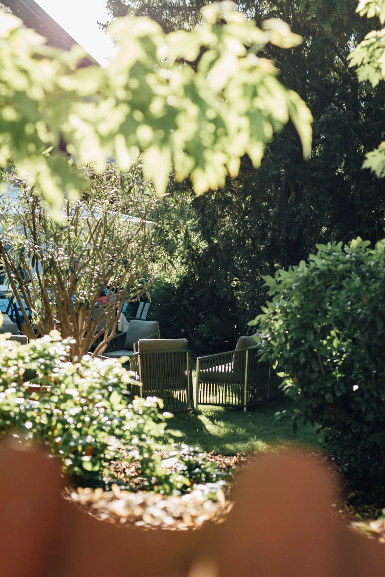Weg durch den Garten des Hotel Krone mit blühenden Sträuchern und Gartenstühlen