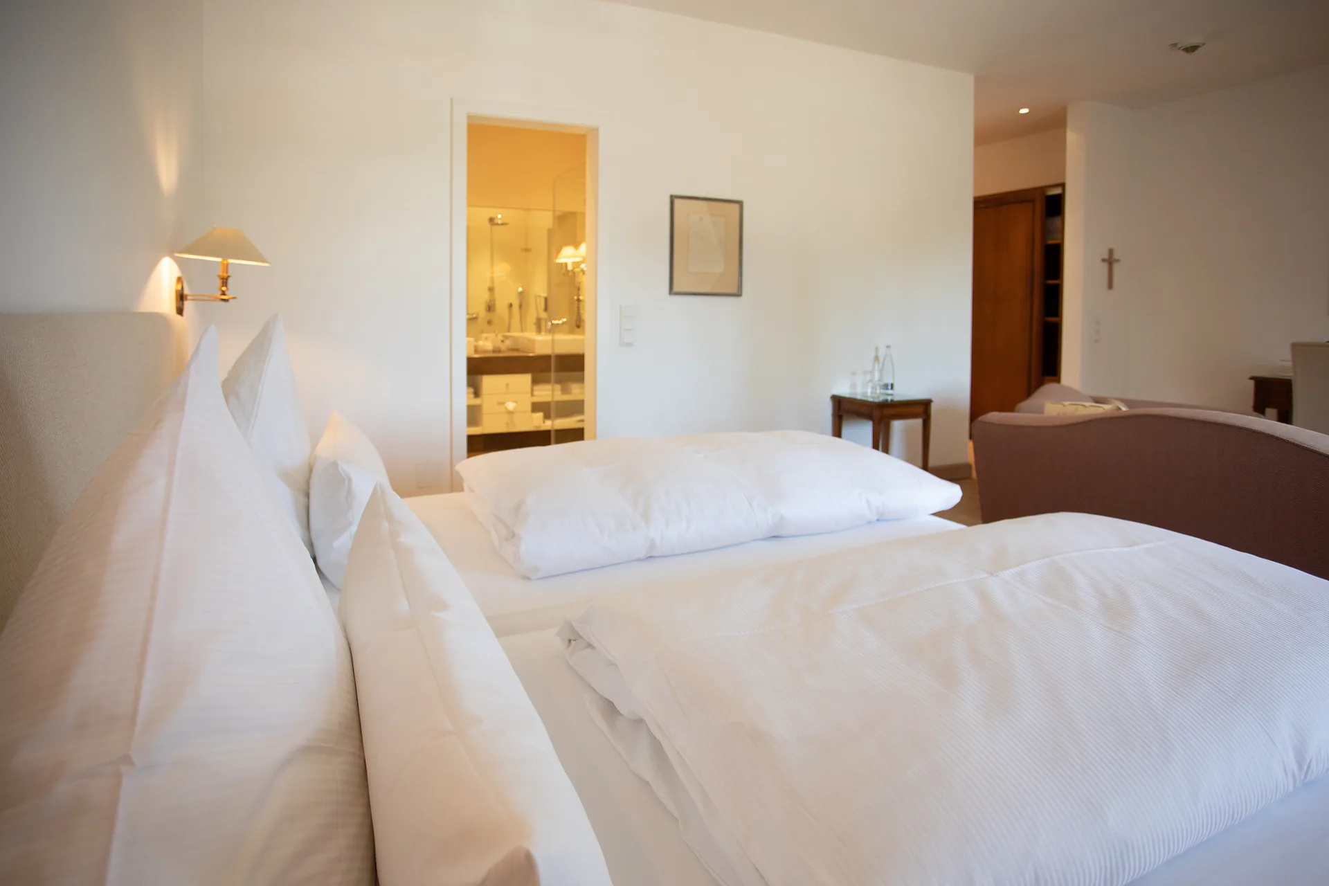 Helle Junior Suite unter dem Dach mit Doppelbett und Blick ins Bad