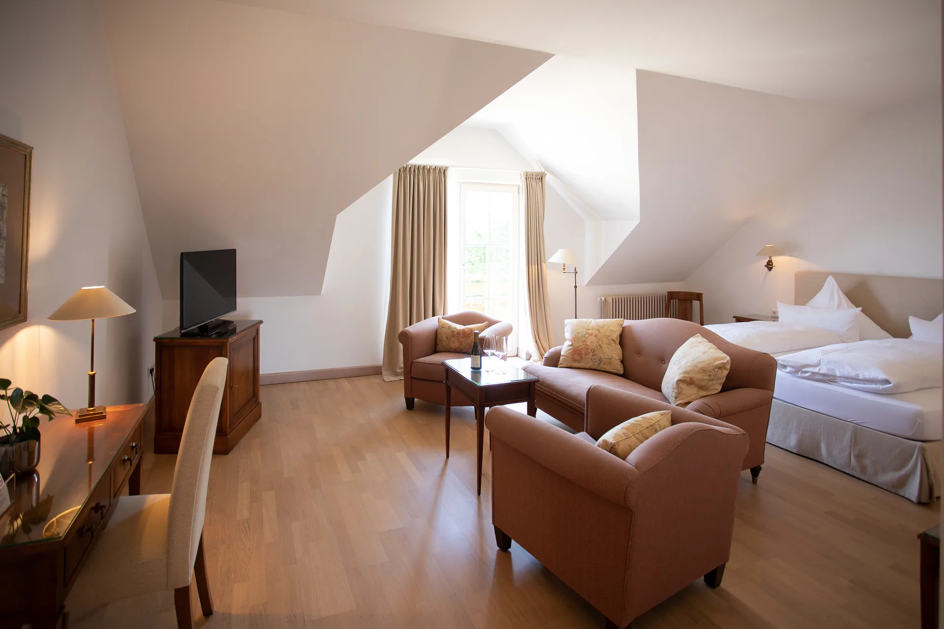 Junior Suite unter dem Dach mit Sitzecke aus braunen Ledersesseln und Doppelbett