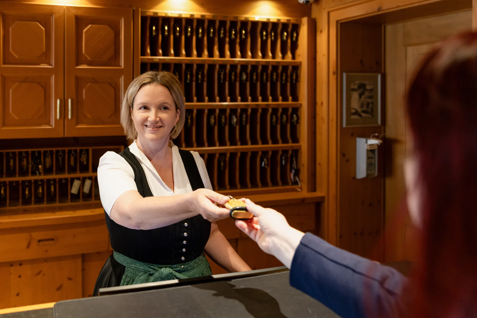 Mitarbeiterin in Tracht übergibt an der Rezeption des Hotel Krone einen Schlüssel