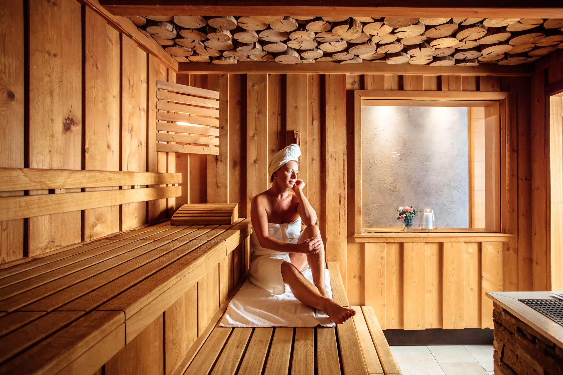 Gast sitzt mit Handtuch in der holzvertäfelten Sauna des Hotel Krone