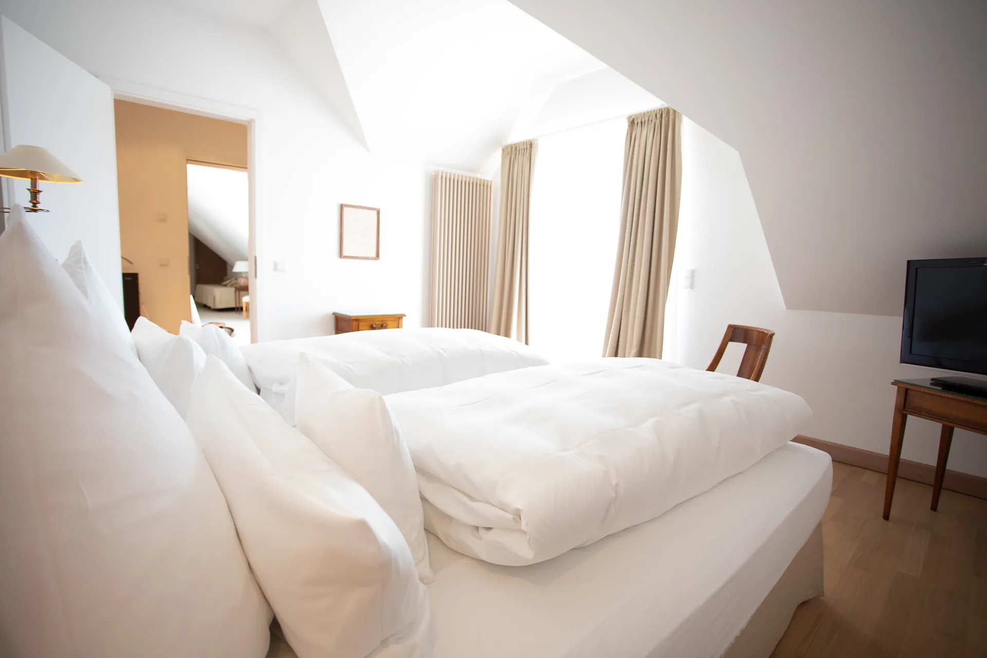 Helle Suite unter dem Dach mit Doppelbett, Fernseher und Blick ins Bad