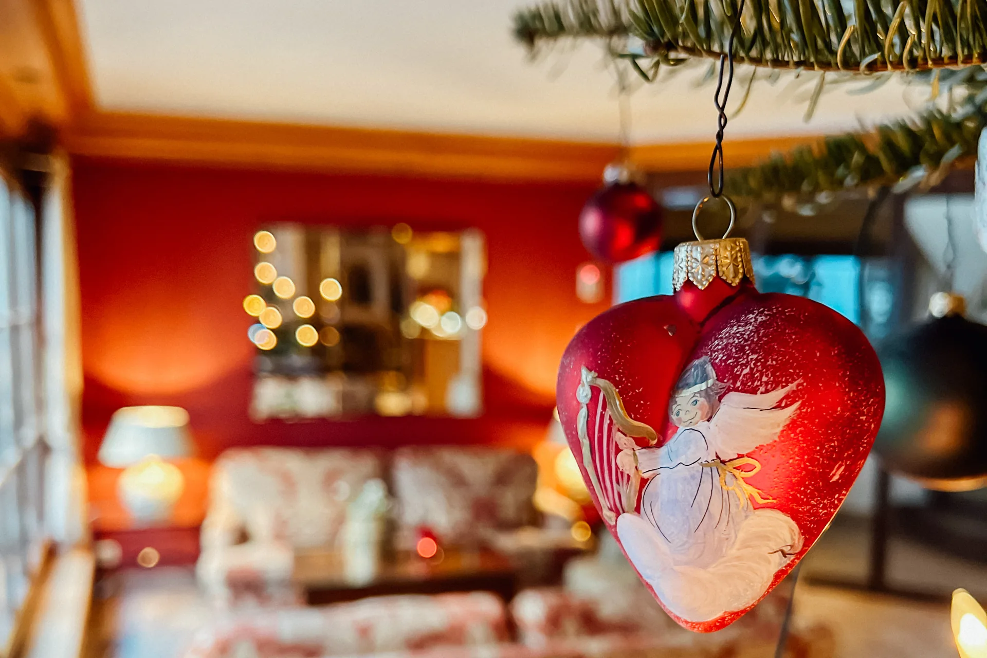 Rote Christbaumkugel vor der weihnachtlich geschmückten Lounge des Hotel Krone